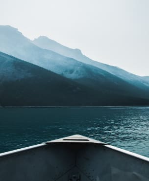 bateau seul au milieu de l'eau avec en arrière plan des montagnes